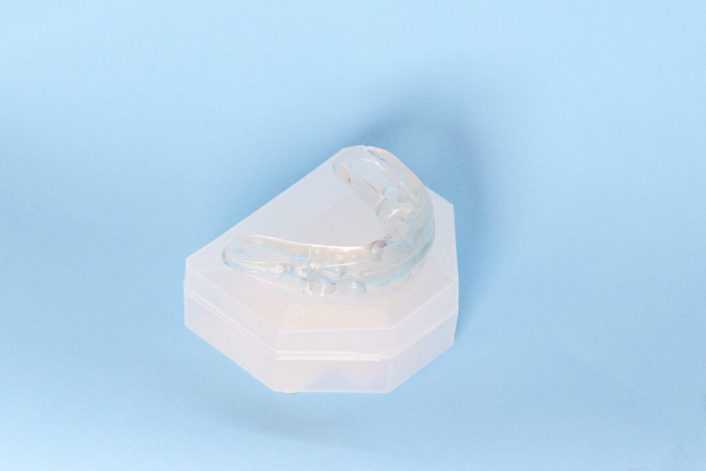 A transparent night guard placed on a dental model against a light blue background.