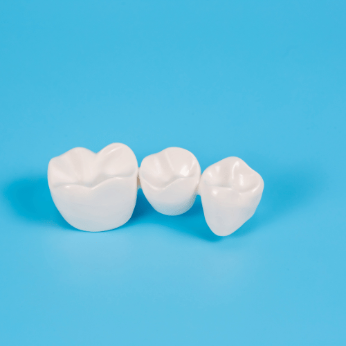 Three white dental crowns displayed on a bright blue background.